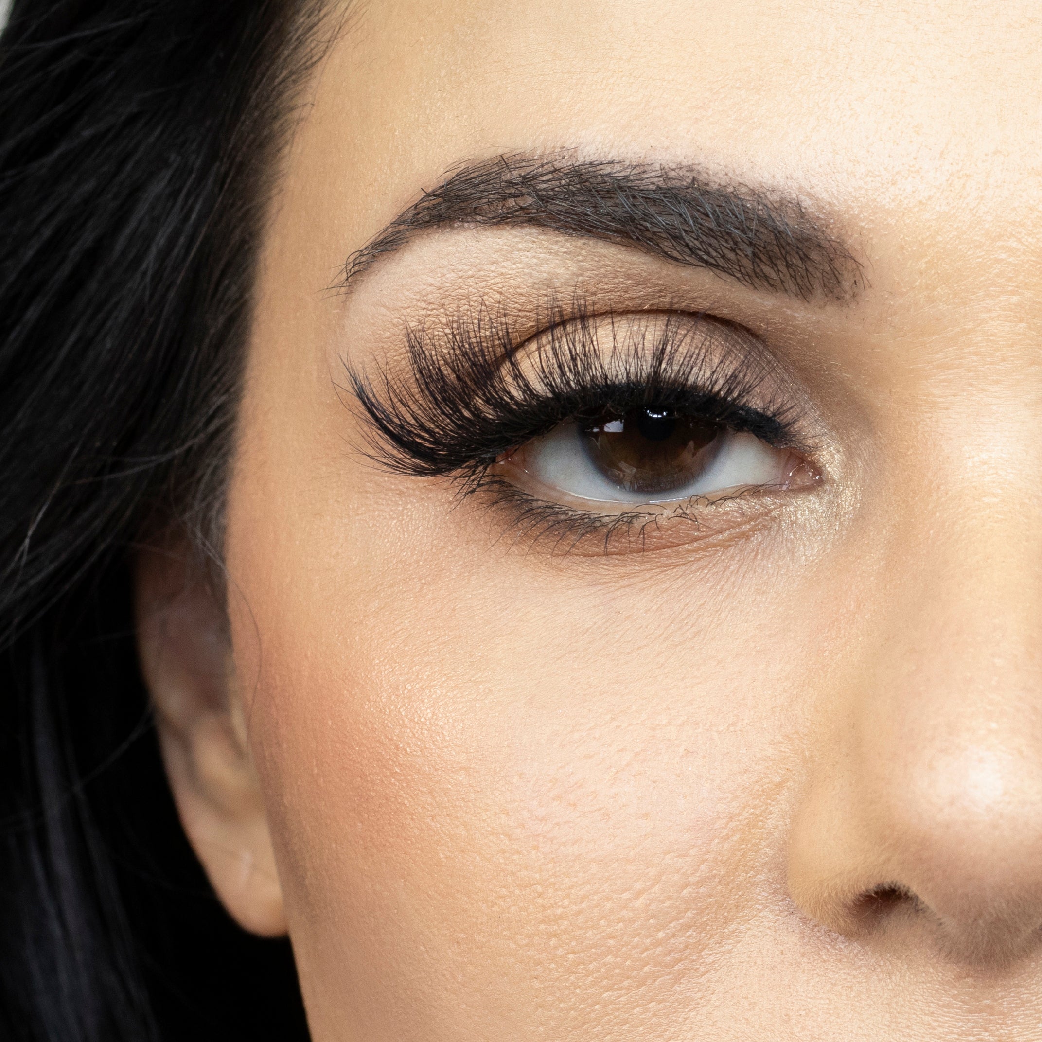 Suntarah Beauty 3D Faux Mink False Strip Eyelash in Style F-106. Close up of young woman wearing lash looking straight ahead.