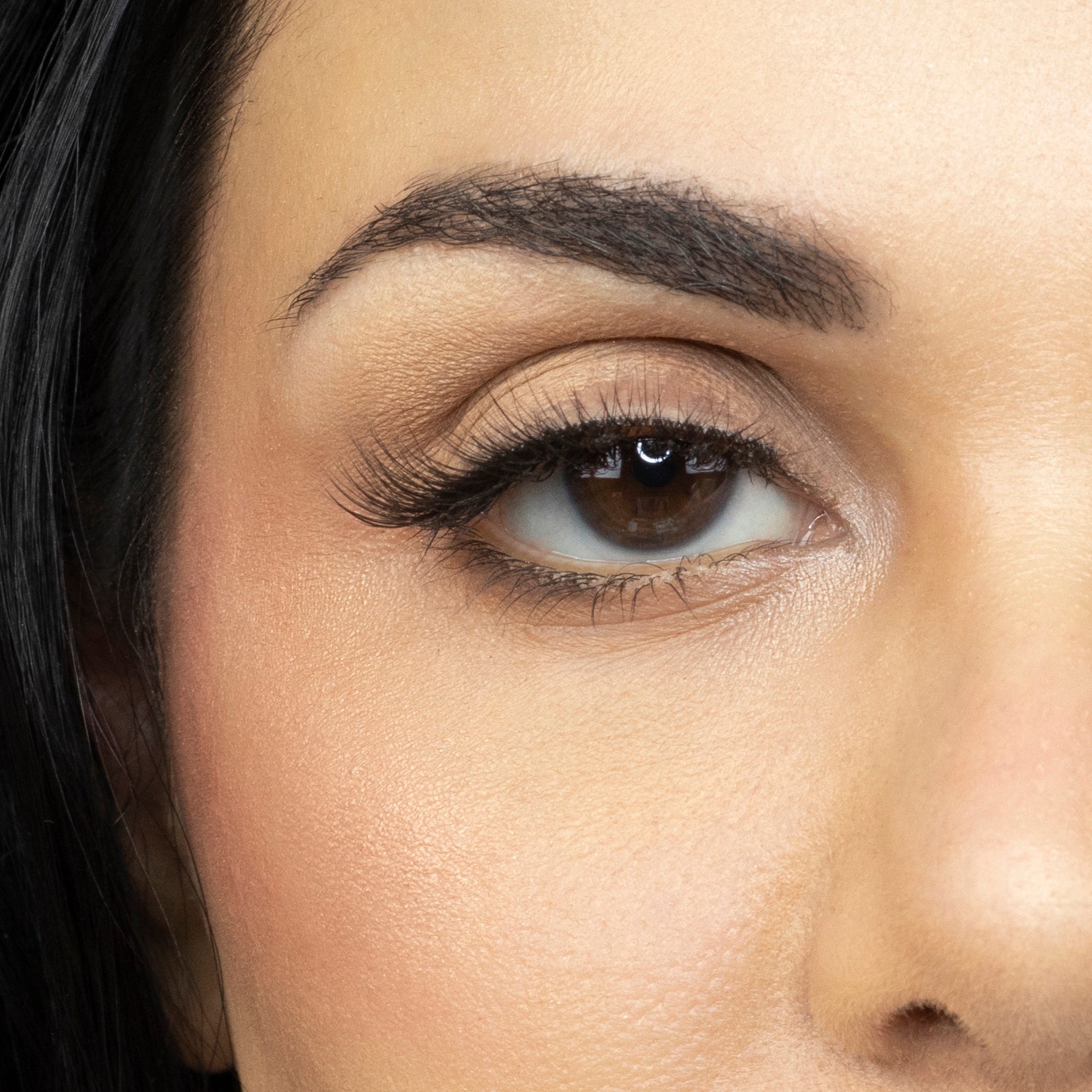 Close up of woman’s right eye while wearing Suntarah Beauty 3D Ultra Light Synthetic false strip eyelash in style SL-332.  Woman is looking straight ahead.  